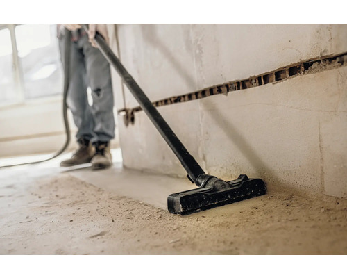 Osoba vysává prach vysavačem na staveništi.