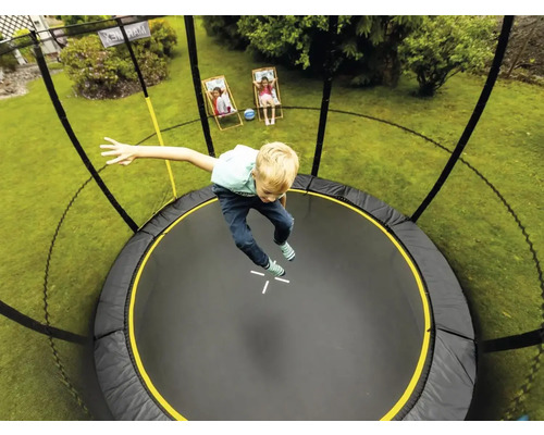 Chlapec skáče na kulaté zahradní trampolíně se sítí
