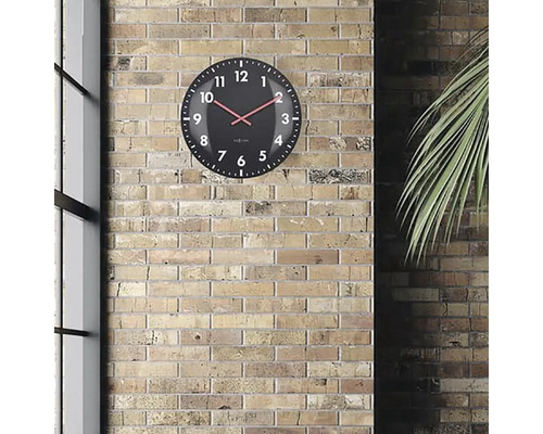 Černé nástěnné hodiny s červenou ručičkou na cihlové zdi