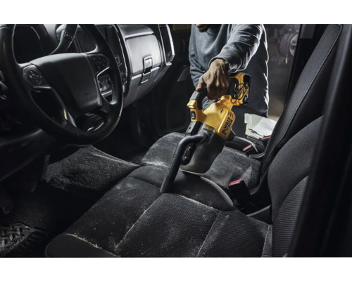 Osoba vysává interiér auta žlutým ručním vysavačem DeWalt.