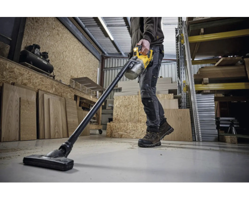 Muž používá akumulátorový vysavač DeWalt v dílně.