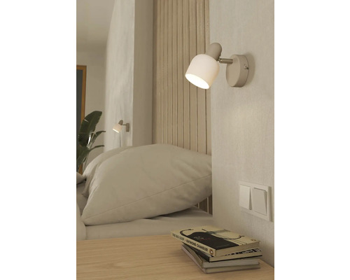 Ložnice s nástěnnou lampou, postelí a nočním stolkem