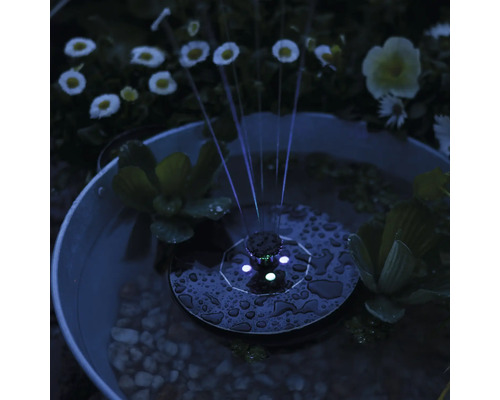 Solární fontána ve vodní nádrži s rostlinami a oblázky