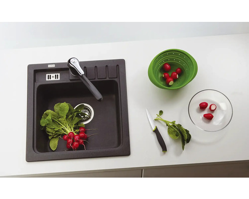 Kuchyňský dřez s vodovodní baterií, ředkvičky v sítu a na talíři