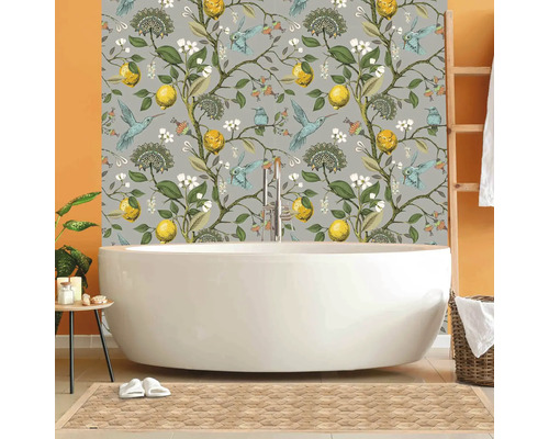 Koupelna s volně stojící vanou před tapetou s motivem citronů a ptáků