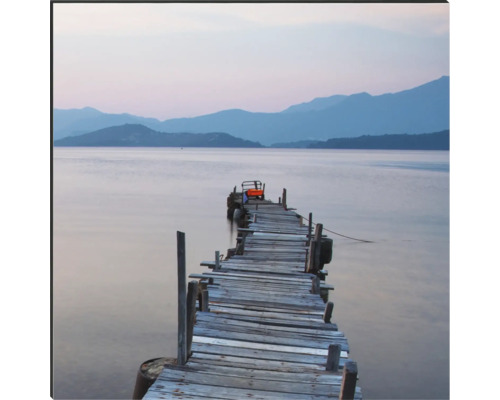 Dřevěná lávka vede do jezera před kopcovitou krajinou.