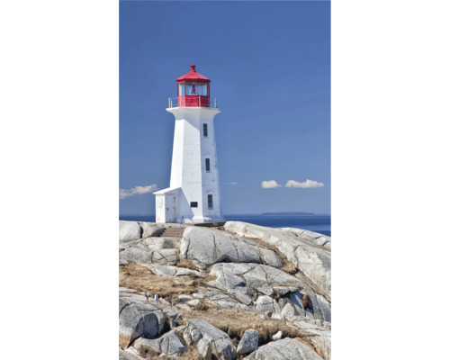 Bílý maják s červeným vrcholem stojí na skalnatém podkladu před modrou oblohou.