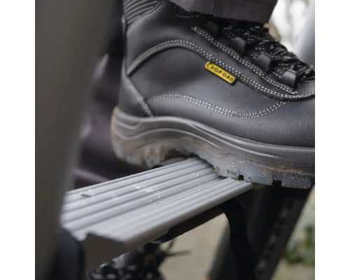 Noha v bezpečnostní obuvi na stupni žebříku.