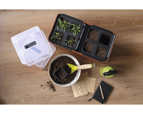 Sada pro pěstování s květináči, zeminou, nářadím, sáčky semen a zápisníkem na dřevěném stole