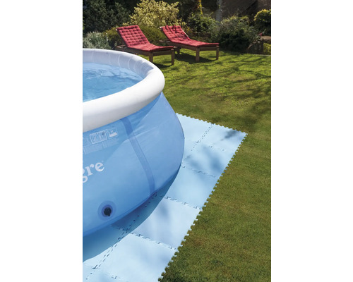 Nafukovací bazén na trávníku s podložkami pod bazén a dvěma lehátky v pozadí.