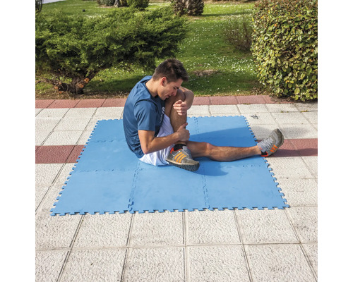 Muž se protahuje na modré cvičební podložce venku
