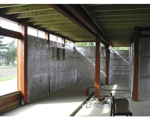 Interiér hrubé stavby s dřevěnými rámy, izolovanými stěnami a betonovou podlahou