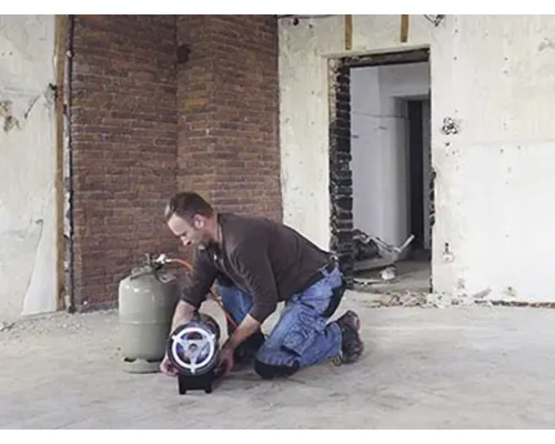 Řemeslník pracuje s plynovým topením v místnosti vyžadující rekonstrukci.