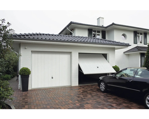 Dvojitá garáž se sekčními vraty a dlážděným příjezdem před domem.