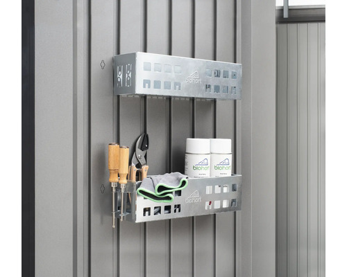 Dvě kovové police s nářadím, čisticími hadříky a spreji na zdi