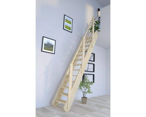 Pohled do místnosti s dřevěným schodištěm u zdi s rámy na obrazy.