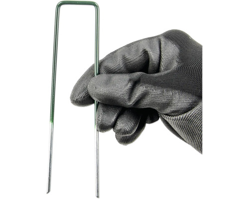 Ruka v zahradní rukavici drží zelený travní hřebík.