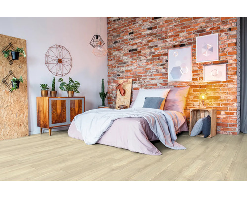 Světlá dřevěná podlaha v ložnici s postelí a cihlovou zdí