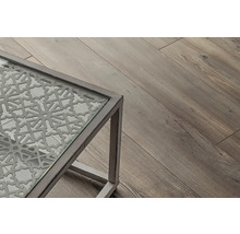 Detailní pohled na stůl se skleněnou deskou a dekorativním vzorem, vedle dřevěná podlaha.