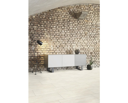 Obývací pokoj s cihlovou zdí, komodou, stojací lampou a dlažbou