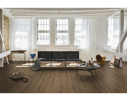 Světlá místnost s dřevěnou podlahou, pohovkou, stolem a okny