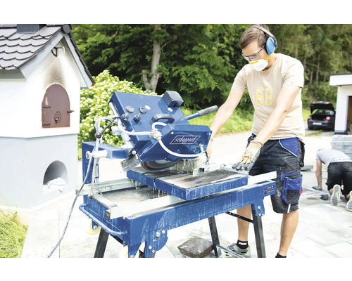 Muž obsluhuje pilu na kámen pro stavební práce venku.