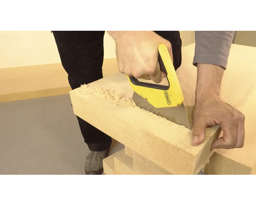 Muž řeže dřevo ruční pilou.