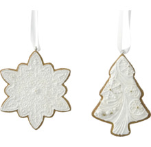 Dva perníkové přívěsky ve tvaru sněhové vločky a vánočního stromku s bílou dekorací a závěsnými stuhami.