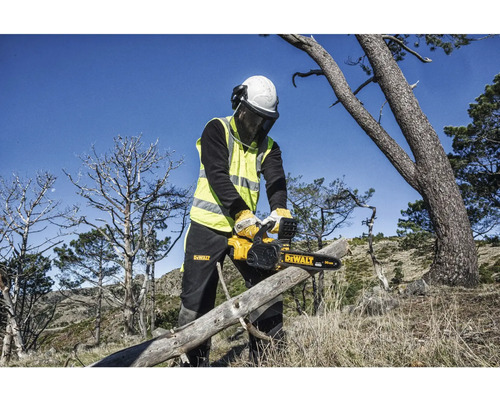 Osoba s ochrannými pomůckami řeže kmen stromu motorovou pilou DeWalt.