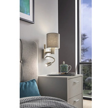 Nástěnná lampa s lampičkou na čtení nad nočním stolkem v ložnici.