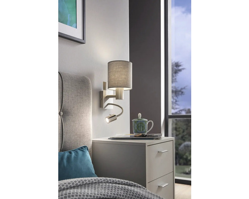 Nástěnná lampa s lampičkou na čtení nad nočním stolkem v ložnici.