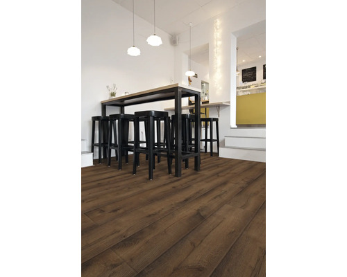 Interiér s tmavou laminátovou podlahou, vysokým stolem a černými barovými stoličkami.