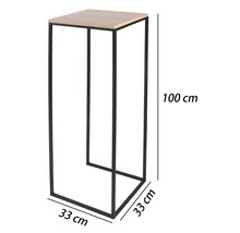 Vysoký stojan na květiny s černým kovovým rámem a světlou deskou v dekoru dřeva, rozměry 100 centimetrů výška a 33 na 33 centimetrů šířka.