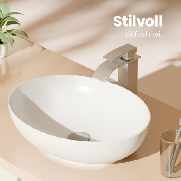 Bílé oválné umyvadlo na desku s moderní pákovou baterií v minimalistické koupelně.