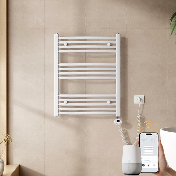 Bílý elektrický koupelnový radiátor na světlé dlážděné stěně, ovládaný přes aplikaci v chytrém telefonu, moderní a funkční design.