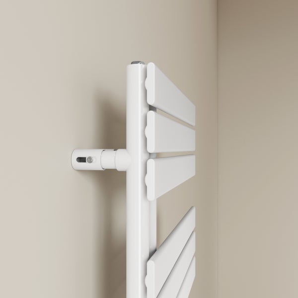 Detailní pohled na bílý radiátor s termostatem na stěně.