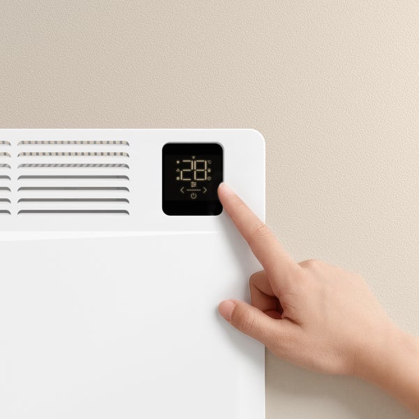 Detailní záběr bílého radiátoru s digitálním displejem ovládaným rukou
