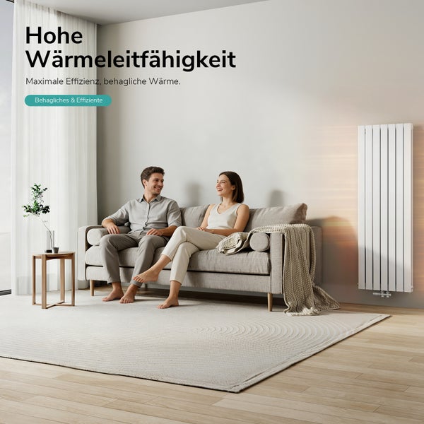 Vertikální designový radiátor ve světlém, moderně zařízeném obývacím pokoji s párem na pohovce.