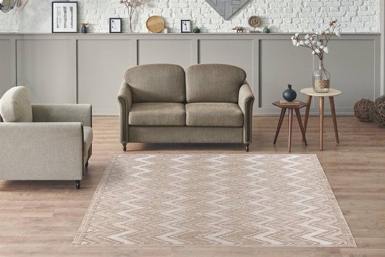 Moderní obývací pokoj s vzorovaným kobercem s klikatým designem na dřevěné podlaze, dvoumístnou pohovkou, křeslem a odkládacími stolky.
