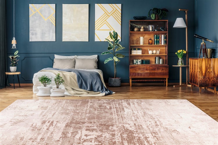 Moderní ložnice s růžovým kobercem ve vintage stylu na dřevěné podlaze, tmavě modrá stěna, dřevěný nábytek, rostliny a organizovaná atmosféra.