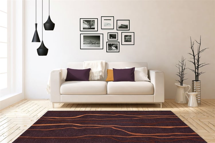 Moderní obývací pokoj se světlou pohovkou, tmavým kobercem s vlnitým vzorem, galerií obrazů a černými svítidly na dřevěné podlaze.