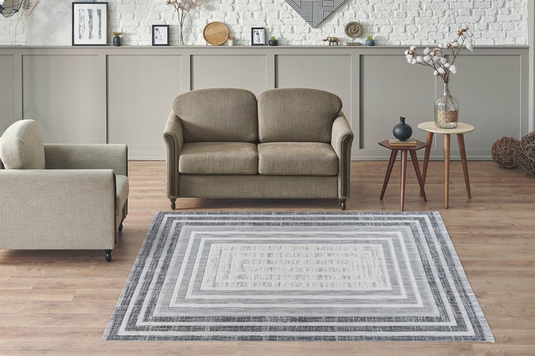 Moderní obývací pokoj s obdélníkovým kobercem s šedým a bílým geometrickým vzorem na laminátové podlaze.