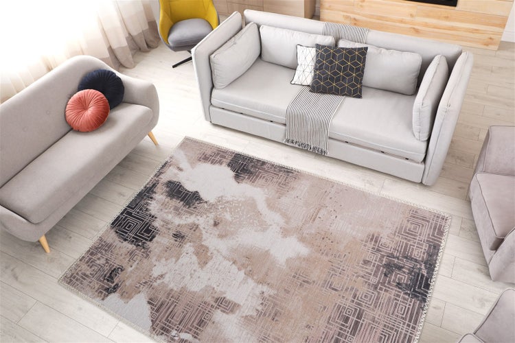 Moderní obývací pokoj se dvěma šedými pohovkami a velkým kobercem s abstraktním geometrickým vzorem na světlé podlaze.
