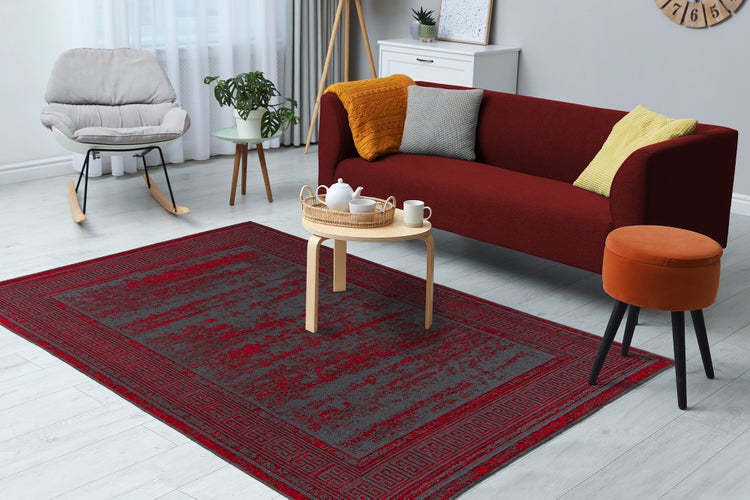 Světlý obývací pokoj s šedo-červeným vzorovaným kobercem na světlé podlaze, červenou pohovkou a moderním nábytkem.