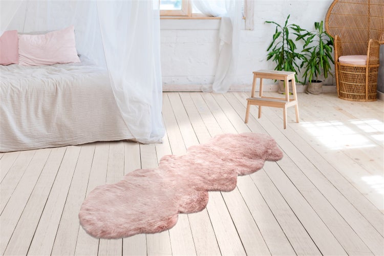 Detailní pohled na růžový koberec z umělé kožešiny s měkkými, dlouhými syntetickými vlákny a hustým vlasem.