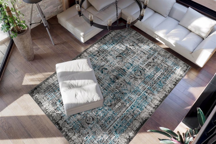 Moderní obývací pokoj s orientálním vzorovaným kobercem v tyrkysové a šedé barvě na tmavé dřevěné podlaze, s bílou rohovou pohovkou.