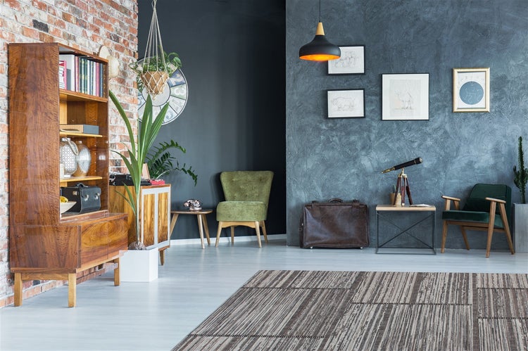 Moderní obývací pokoj s cihlovou stěnou, dřevěnou skříní, modrou stěnou, zelenými křesly, pruhovaným kobercem a vintage dekorací.