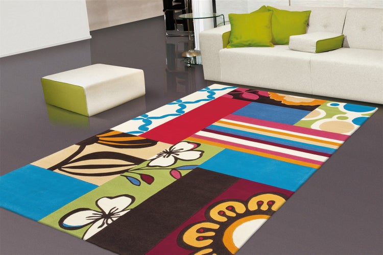 Barevný patchwork koberec s květinovými, pruhovanými a bodkovanými vzory v moderním obývacím pokoji s bílou pohovkou.