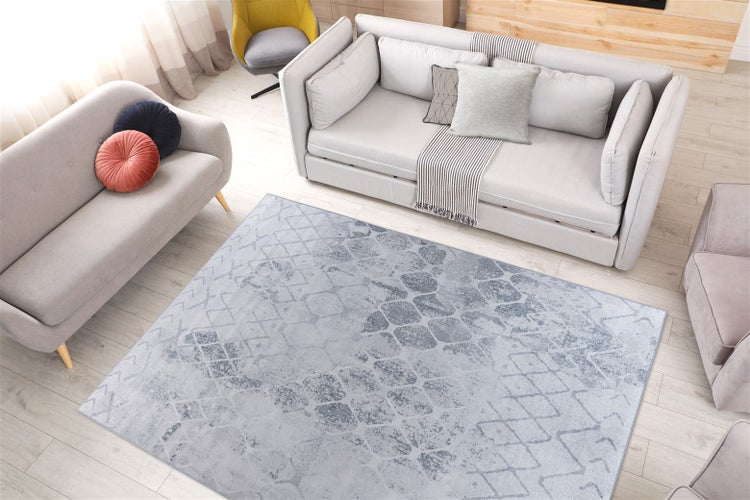 Obdélníkový koberec s moderním geometrickým vzorem ve stylu vintage ve světlém obývacím pokoji na dřevěné podlaze.