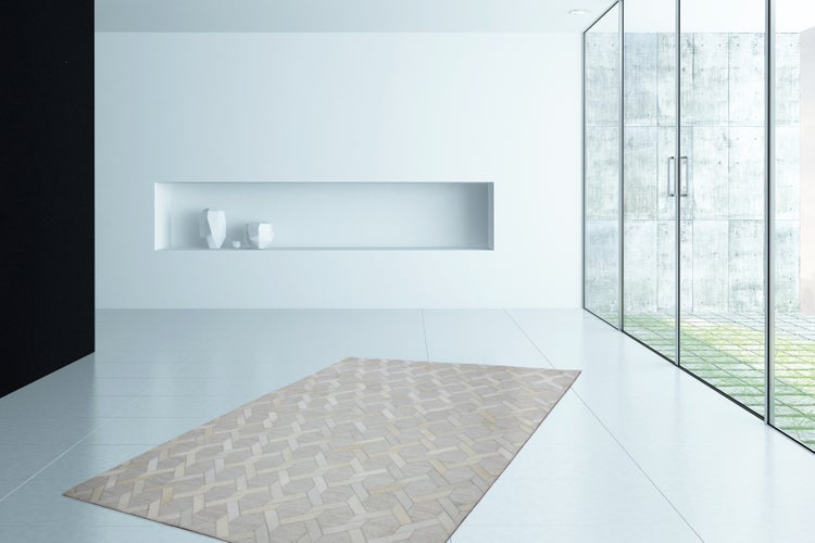 Moderní světlý pokoj s kobercem s geometrickým vzorem na dlážděné podlaze, výklenkem ve stěně a velkými prosklenými dveřmi.